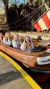 A montage of clips featuring a group of children enjoying a day out at Legoland, including shots on various rides and posing for photos.