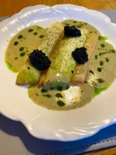 A high-quality, close-up shot of a sophisticated vegetarian dish featuring leeks and rhubarb, served with a kelp butter sauce and seaweed caviar. The presentation is elegant and reflects a fine dining standard, likely from a private dining experience.