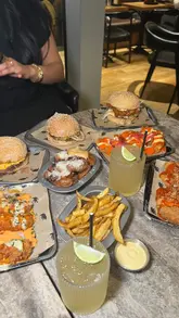 A short, fast-paced montage showcasing a variety of dishes from a collaboration between Black Bear Burger and The Creators Table. The video features close-up shots of burgers, loaded fries, wings, and unique items like Philly cheese Yorkshire puddings, presented in a casual, social setting.