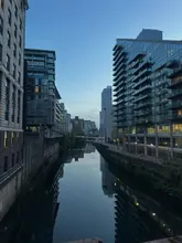 A serene, high-quality landscape photograph capturing a calm canal at twilight, flanked by modern city architecture, including The Lowry Hotel. The composition is balanced and symmetrical, utilizing the reflection in the water to create a peaceful, atmospheric mood.