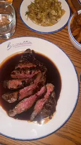 A creator visits Bavette, a neighborhood bistro in Horsforth, showcasing the interior, the open kitchen, cocktails, and a variety of dishes including steak, artichoke tart, and a chocolate dessert. The video highlights the vibrant atmosphere and the quality of the food.
