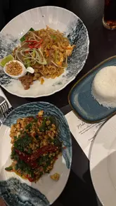 A creator visits Sukhothai restaurant to review their new menu and refurbished interior. The video features shots of the restaurant's atmosphere, close-ups of various Thai dishes including pad thai and pad ga prao, and the creator's personal feedback on the food and dining experience.