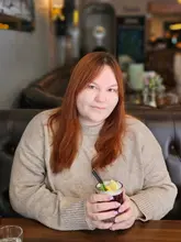 A portrait of a customer holding a cocktail at a restaurant, likely taken for a social media review.