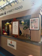 A clear, eye-level shot of the Patagonia Street Food stall in a market setting, showcasing the menu board and the stall's branding. The image provides a good overview of the venue's aesthetic and offerings.
