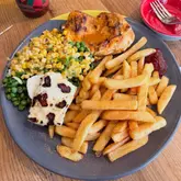 Nando's peri-peri butterfly chicken, grilled halloumi, sweetcorn, peas, and chips on a plate.