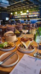 A vibrant spread of Eightfold Dim Sum dishes: roast duck bao, black pepper sirloin, and a lychee martini cocktail in Bristol.