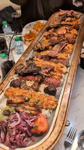 A promotional reel for Chef Burak Gurme in Birmingham, featuring a large Ottoman platter of grilled meats. The video uses fast-paced, handheld shots to showcase the food, the restaurant interior, and the social dining experience.