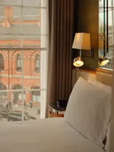 A serene, high-quality photograph capturing a cozy hotel room interior at the Great Northern Hotel in London. The shot features a warm, inviting bedside lamp and a view out of the window towards the historic architecture of the King's Cross area, emphasizing a calm, relaxing atmosphere amidst the city's bustle.