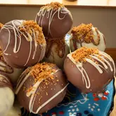 A close-up, natural-light shot of homemade Biscoff cake truffles. The image effectively showcases the texture of the chocolate coating and the crumb topping, making for an appealing home-cooking post.