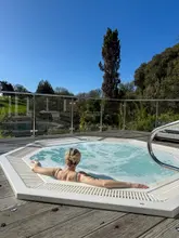 A lifestyle shot taken from behind a person relaxing in an outdoor hot tub, looking out over a green landscape at the Budock Vean Hotel.