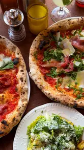 A promotional video for Rudy's Pizza Napoletana in Sutton Coldfield, featuring a montage of the restaurant's exterior, interior, menu, and various food and drink items including pizza, burrata, and cocktails.
