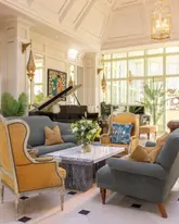A high-quality, well-lit interior photograph of a hotel lounge area, featuring comfortable seating, a grand piano, and elegant decor. The image showcases the 'Garden Lounge' at Barberstown Castle Hotel, highlighting its contemporary design within a historic setting.