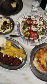 A review of Taverna Ermou in London, showcasing various Greek dishes including dips, skewers, salads, and desserts. The video highlights the authentic atmosphere and specific menu recommendations.