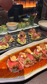 A high-quality, fast-paced montage showcasing a bottomless brunch experience at Sticks'n'Sushi, featuring a wide array of Japanese dishes, cocktails, and the restaurant's interior.