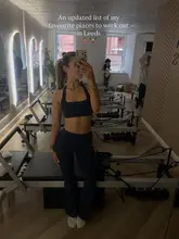 A mirror selfie taken inside a Pilates studio, used as the cover image for a listicle-style post recommending various fitness venues in Leeds. The creator is positioned centrally, showcasing the studio environment.