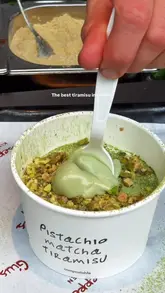 A short, visually focused clip demonstrating the assembly of a pistachio matcha tiramisu at a street food stall. The video highlights the preparation process, including dusting with matcha, adding crushed pistachios, and drizzling pistachio cream.
