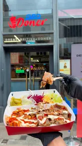 A promotional video for Great British Doner in Manchester, highlighting their robot-cut doner kebab preparation, including the assembly of wraps and boxes, and showcasing the venue's exterior.