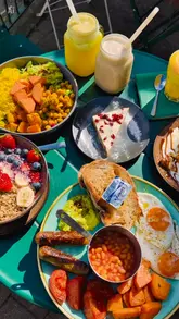 A high-energy, vlog-style review of 50Nine in St Albans, showcasing a variety of breakfast and lunch options including a full English breakfast, samosa chaat, buddha bowl, and healthy smoothies.