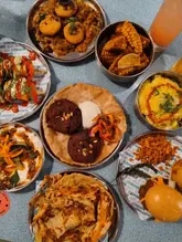 A top-down, flat-lay photograph showcasing a variety of Indian street food dishes from Bundobust, including pav bhaji, corn frites, and vada pav sliders.