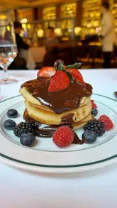 A short, polished montage showcasing the brunch menu at Smith & Wollensky, featuring close-ups of pancakes, beef brisket with Yorkshire pudding, and hash browns, set within the restaurant's interior.