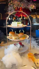A short, polished montage showcasing an afternoon tea service at Coco Tower Bridge. The video features slow-motion shots of tea being poured, a smoking cocktail, the tiered food stand, and the venue's interior and exterior views of Tower Bridge.