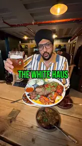 The creator visits The White Haus in London, an Alpine-themed bar, to review their food and atmosphere. The video features a tour of the venue, highlighting the ski-themed decor and private dining area, followed by a detailed showcase of their Indian-inspired menu, including a large mixed grill, various chicken dishes, wraps, and sides.