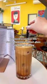 A short, aesthetic video highlighting the interior of a cafe, specifically its stained glass ceiling, alongside shots of an iced coffee and a chicken wrap with fries.