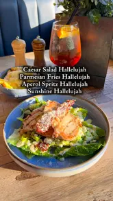 A short, handheld video showcasing a Caesar salad, parmesan fries, and an Aperol Spritz, presented as a 'girl dinner' option.