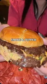 A short, fast-paced montage showcasing a visit to Smoke & Pepper. The video features close-up shots of a smash burger, loaded fries with sauce being poured, and a milk cake dessert, alongside brief glimpses of the venue's interior, menu, and exterior.