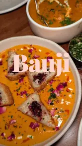 A montage-style video showcasing the interior and various dishes at Bauji restaurant in Worthing. The video features high-quality, slow-paced shots of Indian-inspired plates, including bhajis, tandoori poussin, and curries, set to music without voiceover or text overlays.