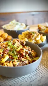 A montage of close-up shots featuring various fried chicken dishes, mac and cheese, and a burger, presented in a casual dining setting.