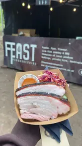 A montage showcasing a variety of street food vendors at an outdoor festival event in the woods, highlighting different cuisines and the family-friendly atmosphere.