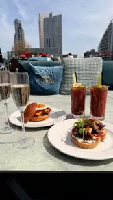 A short, energetic reel showcasing a bottomless brunch experience at a rooftop venue in London. The video features a variety of dishes including a seafood platter, brunch items, and desserts, alongside cocktails and champagne. It highlights the rooftop setting and city views, positioning the venue as an ideal spot for a social brunch.