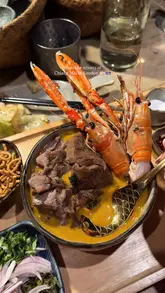 A high-quality montage of Thai dishes, specifically Khao Soi, being prepared and plated at a London restaurant. The video focuses on close-ups of the food, including grilled skewers, braised beef, langoustine, and a pandan ice cream dessert.