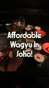 The video features a high-quality, cinematic montage of a Japanese Wagyu BBQ dining experience. It focuses on close-up shots of raw, marbled beef, the tabletop grilling process, and wine pairings, creating an inviting and premium atmosphere.