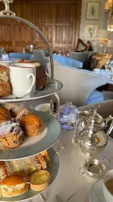 A slow-paced, aesthetic montage showcasing an afternoon tea experience at a 5-star hotel, featuring shots of the drawing room, the tea service, and the surrounding gardens.