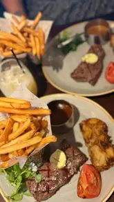 A video tour of a Miller & Carter steakhouse, featuring shots of the restaurant interior, the menu, and a meal consisting of calamari, rump steak with fries and onion loaf, and cocktails.