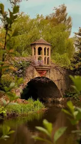 A montage of scenic shots of Dunsborough Park, featuring a stone bridge, a greenhouse, and various flowers, presented as a secret garden near London.