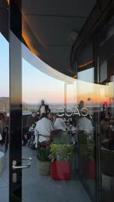 A short, atmospheric montage showcasing a rooftop bar and restaurant at sunset. The video features shots of the venue's exterior and interior, groups of friends enjoying drinks and small plates, and close-ups of sushi and cocktails. The editing is rhythmic and aligns with the music, creating an inviting and trendy vibe suitable for social gatherings.