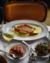 A beautifully composed, high-quality shot of a seafood lunch. The lighting is soft and natural, highlighting the textures of the fish and the freshness of the side dishes. The composition is balanced, capturing the essence of a refined dining experience without feeling overly staged.