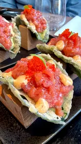 A high-quality food reel showcasing a tasting menu at FAN in Notting Hill, featuring Japanese-Peruvian fusion dishes like sashimi, tempura tacos, and katsu sandwiches. The video uses close-up, handheld shots to highlight the textures and presentation of the food, with appearances from the creator and their child.