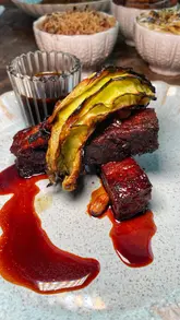 A montage-style reel showcasing a Caribbean restaurant, featuring cocktails, interior shots, and a variety of dishes including curry goat and pork belly.