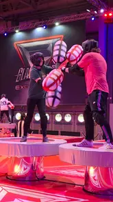 A promotional video featuring a participant navigating the Gladiators obstacle course at the NEC Birmingham, showcasing various challenges like climbing, balancing, and pugil stick fighting.
