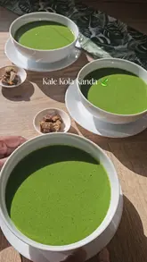 A step-by-step recipe tutorial for making Kale Kola Kanda, a Sri Lankan herbal porridge. The video shows the ingredients, the blending process, and the final plating, accompanied by text overlays explaining the steps.