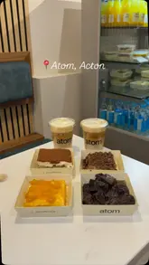 A montage of various food and drink items served at Atom cafe, including sandwiches, cakes, and specialty coffees, presented in a series of static and slow-panning shots.