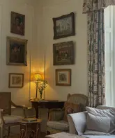 A warm, inviting interior shot of a country house hotel corner, featuring soft lamp lighting, framed artwork, and comfortable seating, creating a peaceful and welcoming atmosphere.