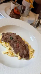 A montage of food, drinks, and interior shots at a restaurant, featuring steak, pasta, and champagne.