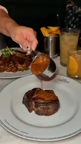 A polished montage showcasing the interior, food, and drinks of an underground brasserie located in a historic vault. The video features high-quality close-ups of various dishes and cocktails, interspersed with shots of the atmospheric dining room.