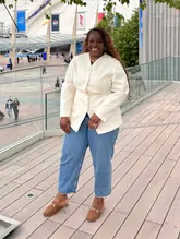 A clear, well-composed portrait of a woman standing on the walkway outside The O2 Arena in London. The image is bright and sharp, effectively capturing the subject against a recognizable landmark, serving as a lifestyle or travel-focused social media post.