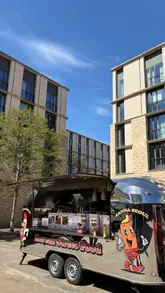 A short, sunny video showcasing a visit to the Manna Seoul Korean street food van. The footage follows the creator walking up to the van, ordering, and enjoying the food, including Korean fried chicken with kimchi and a cheese-filled corn dog.